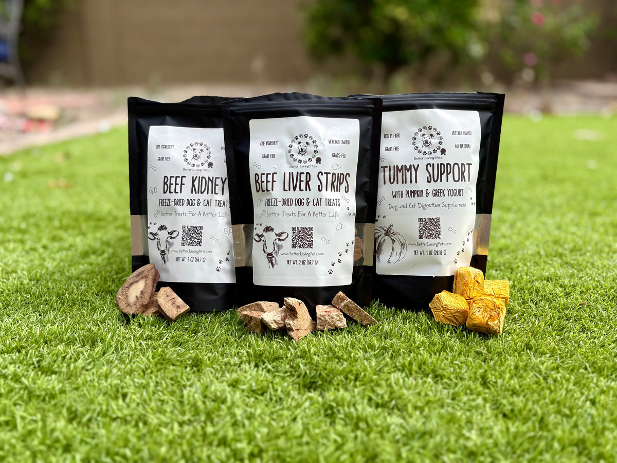 Three packages of pet food on grass with visible branding and product names.